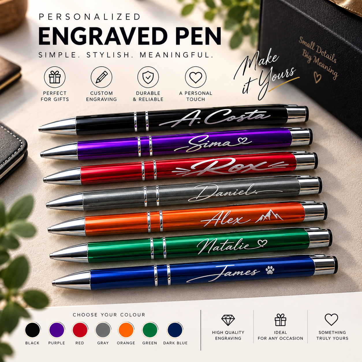 Seven personalized engraved ballpoint pens in different colors are displayed on a light beige surface with decorative props. The pens include black, purple, red, gray, orange, green, and dark blue, each with custom white script names engraved on the barrels.