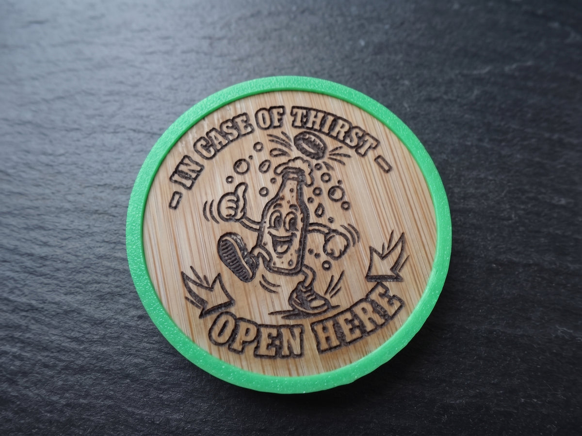 A round wood opener with a green border, featuring a cartoon bottle character and the text 'IN CASE OF THIRST OPEN HERE' on a dark slate background.