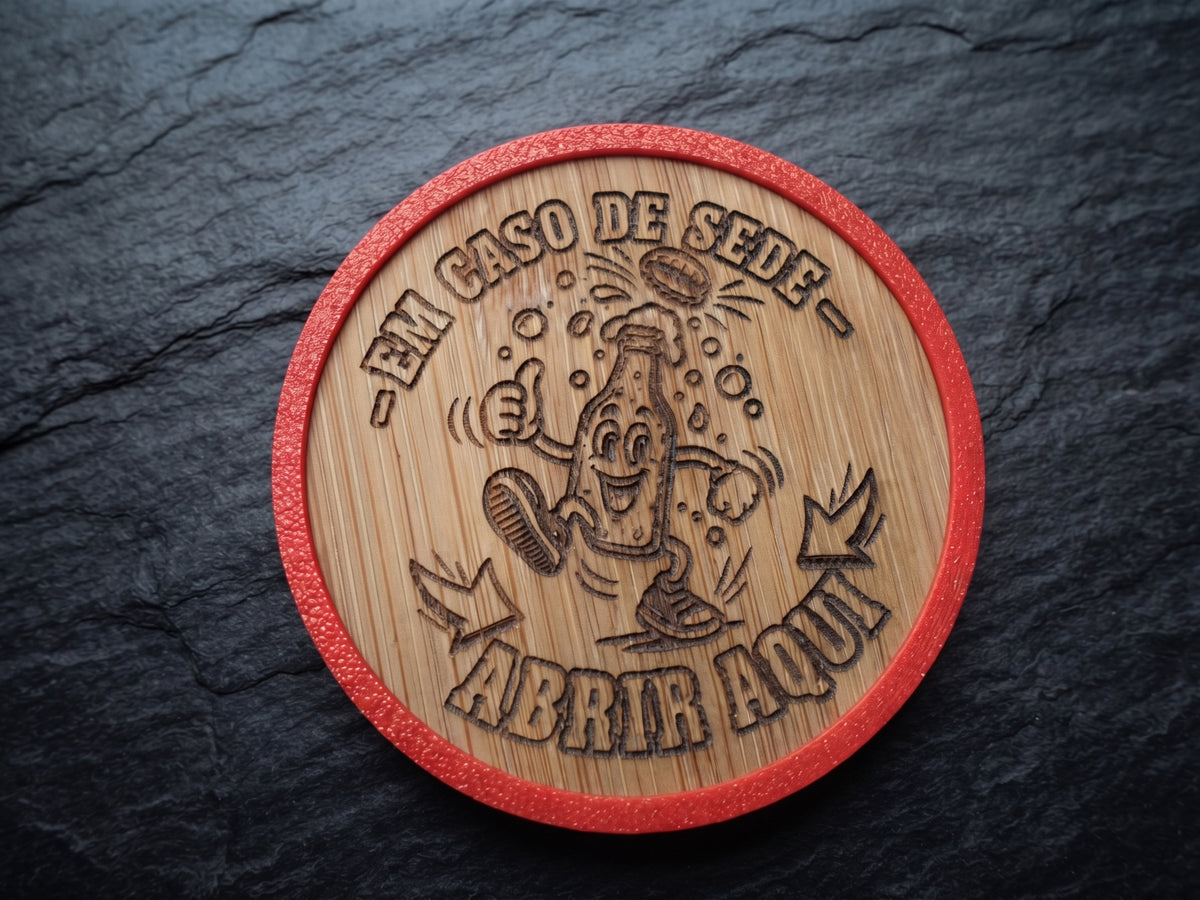 A round wooden opener with a red textured border, featuring a laser-engraved cartoon bottle character and the Portuguese text '-EM CASO DE SEDE - ABRIR AQUI', displayed on a dark slate background.