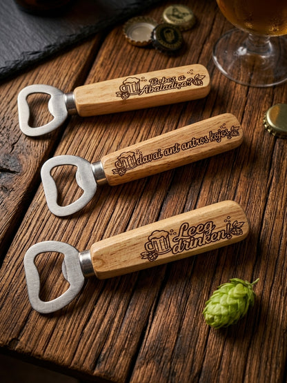 Three personalized wooden bottle openers, arranged diagonally on a rustic dark wood table with beer-themed props including a glass of amber beer, bottle caps, and a green hop cone.
