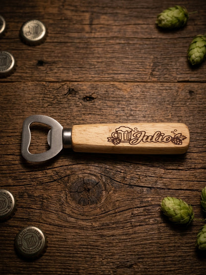 A wooden bottle opener with a custom engraved handle featuring a beer mug and the name 'Julio', displayed on a rustic dark wood background with beer bottles and hops scattered around.