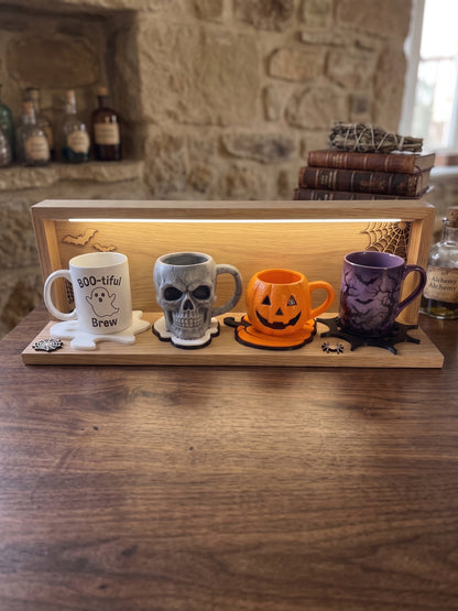 Set of Halloween coasters displayed with skull, ghost and pumpkin mugs on a wooden table.