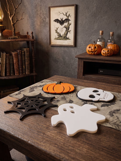 Halloween-themed decorative coasters on a wooden table, including a black spiderweb, an orange pumpkin, a white skull, and a white ghost, set in a rustic room with books and pumpkins.
